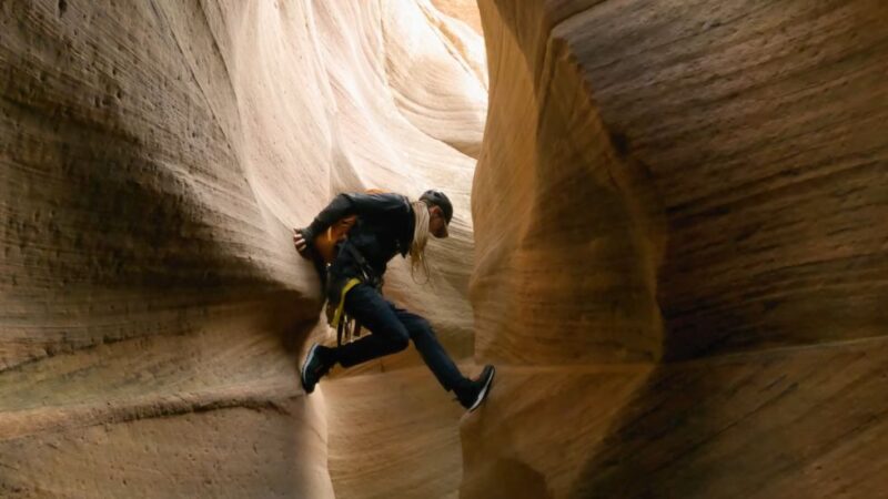Canyoneer wedged between smooth canyon walls inside Keyhole Canyon, Zion National Park