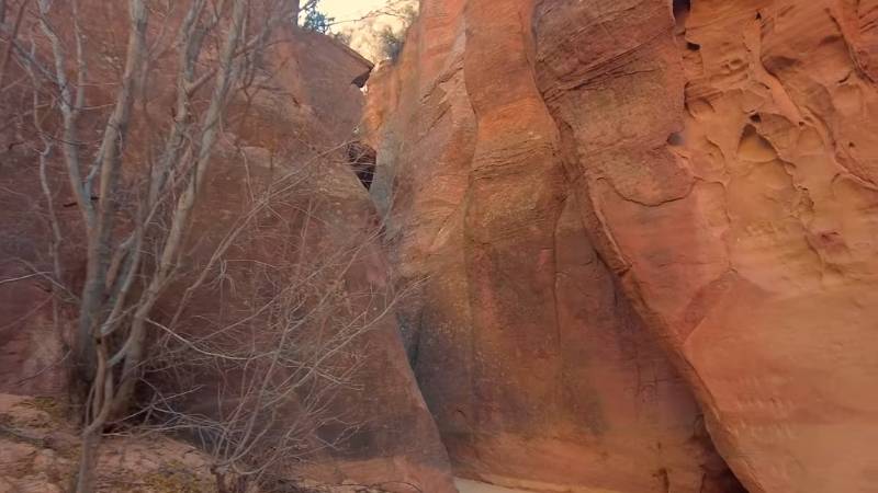 Narrow red sandstone walls winding through Red Hollow Slot Canyon