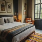 Warm, stylish hotel room with a large bed, leather chair, and window view