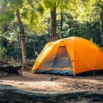 Bright orange tent set up in a forest campsite near Arches National Park