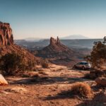 Scenic desert campsite in Canyonlands National Park with a tent and car overlooking rocky formations at sunset