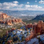 Snow-dusted red rock formations at Bryce Canyon with pine trees and blue sky