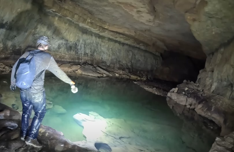 A turquoise pool reflects the cave's damp