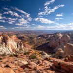 Scenic view of Grand Staircase-Escalante National Monument with red rock formations and a wide desert valley under a blue sky