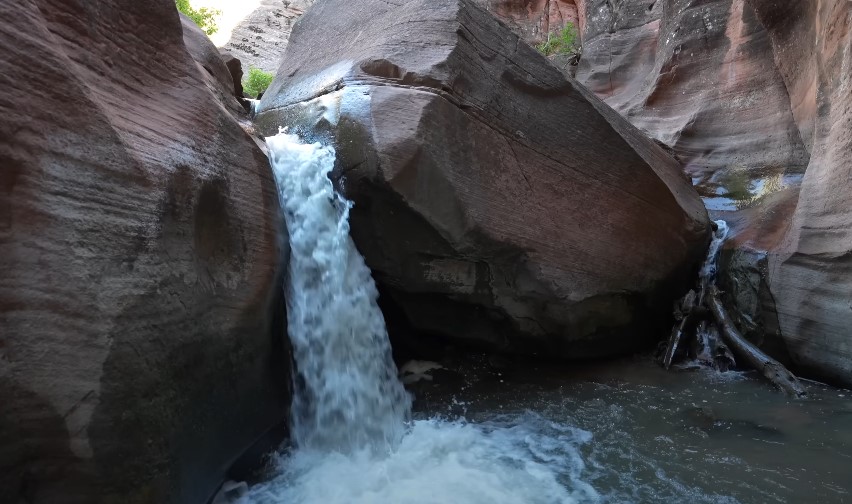 A turquoise pool reflects the cave's damp, dark walls
