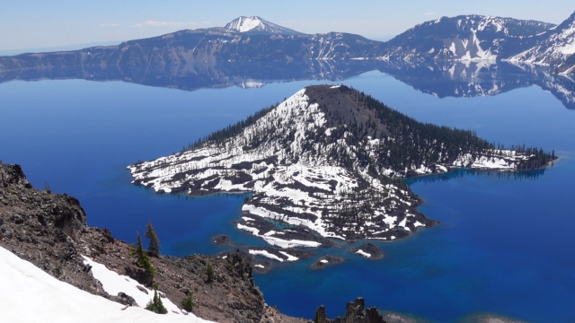 Snow-dusted Wizard Island rises from the deep blue waters of Crater Lake