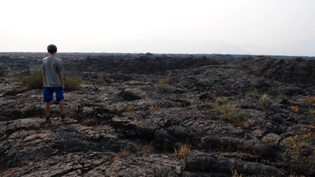 A person stands on the rough, black lava fields of Craters of the Moon National Monument