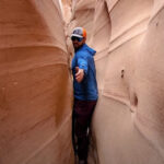 A hiker navigates the narrow passage of Zebra Slot Canyon