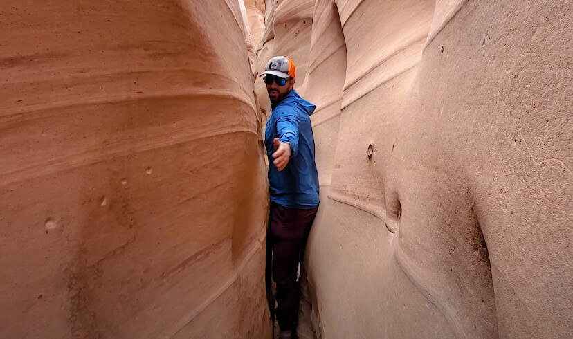 A hiker navigates the narrow passage of Zebra Slot Canyon