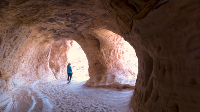 Person walking inside Moqui Caverns sandstone tunnel