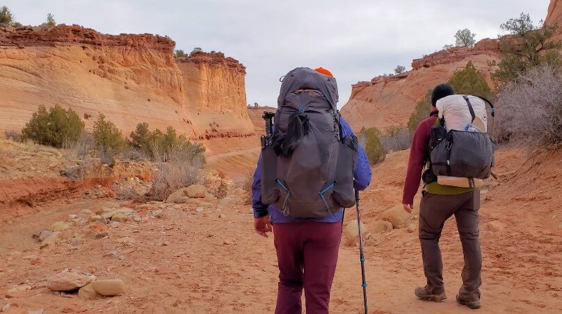 Hikers navigate the sandy trail of Zebra Slot Canyon