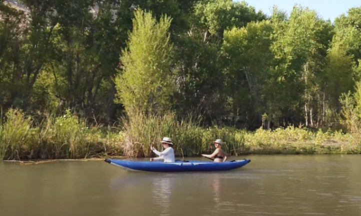 Two persons in a blue kayak, cruising down the river