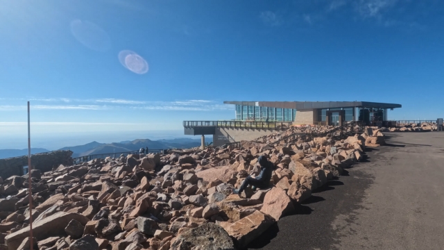 The modern Summit Visitor Center stands atop Pikes Peak surrounded by rocky terrain and clear mountain views