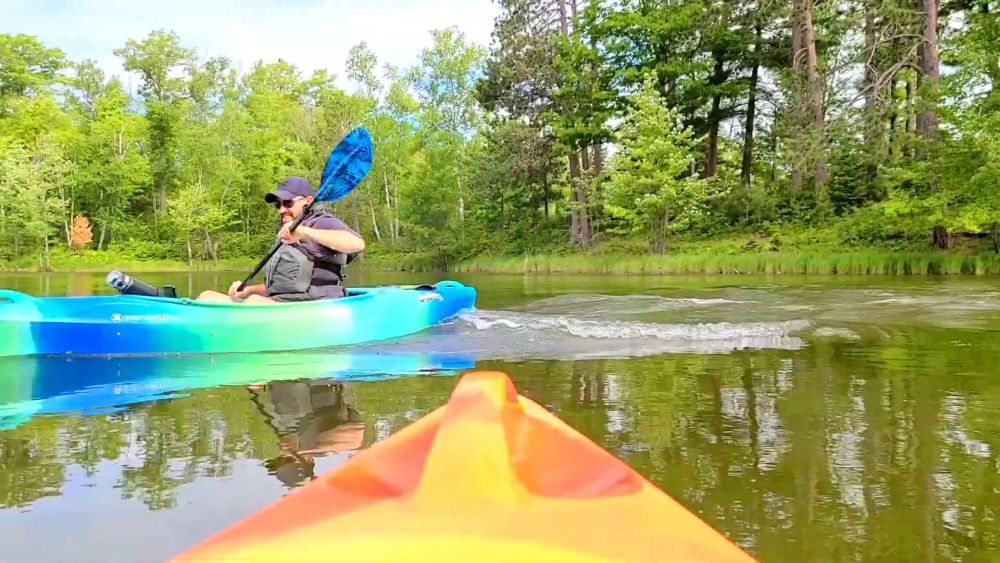 Kayakers paddling on calm forest lake water in Savanna Portage State Park