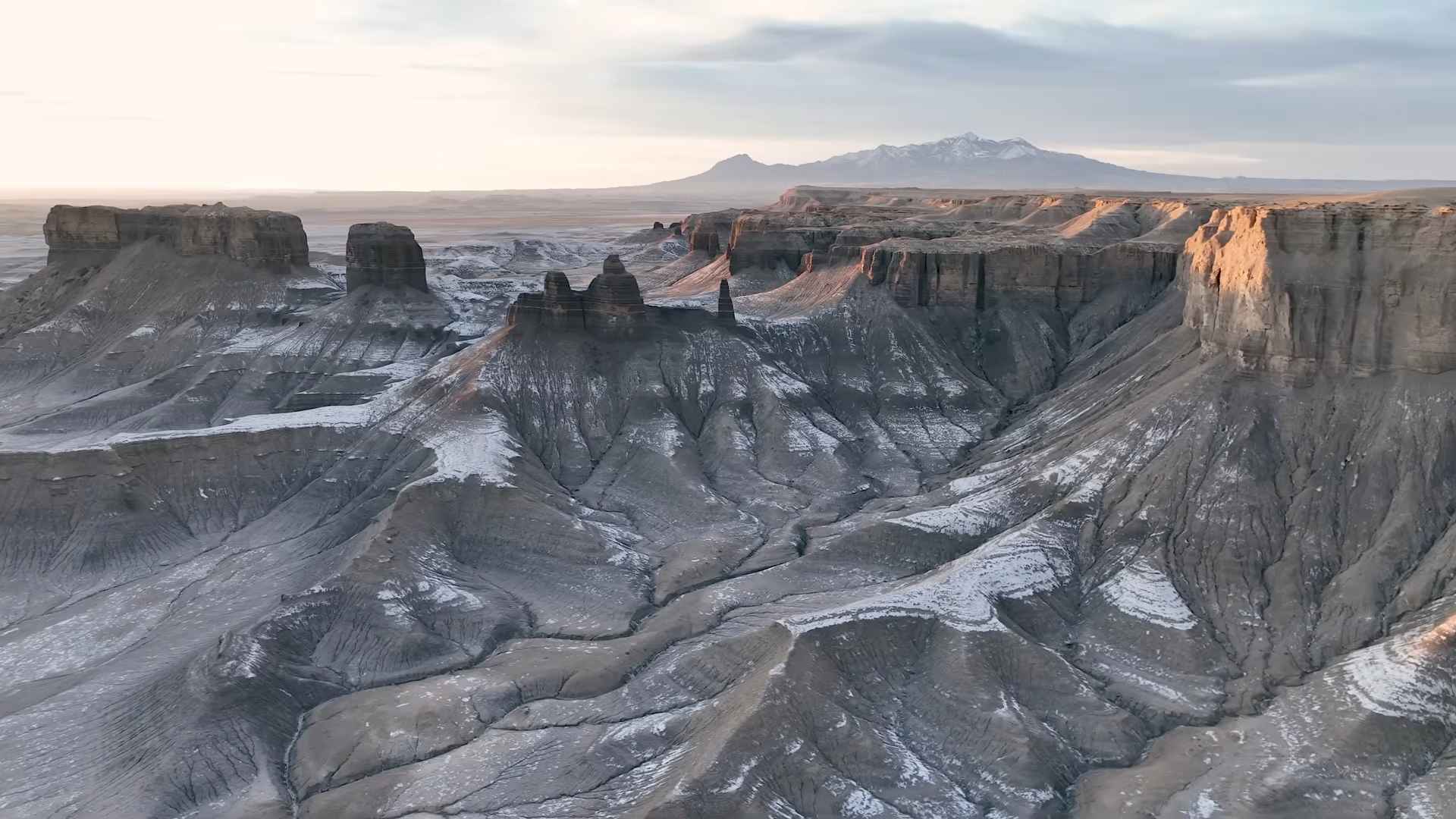 Gray eroded cliffs and mesas stretching across a barren desert landscape