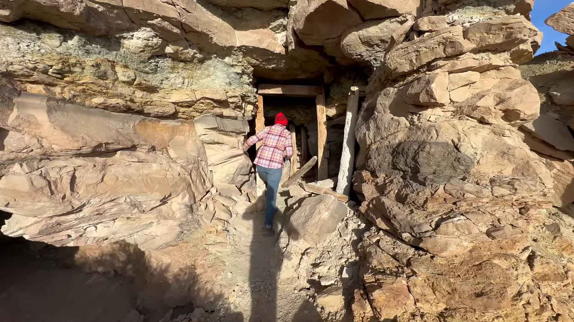 Person entering a small cave opening in a rocky desert landscape