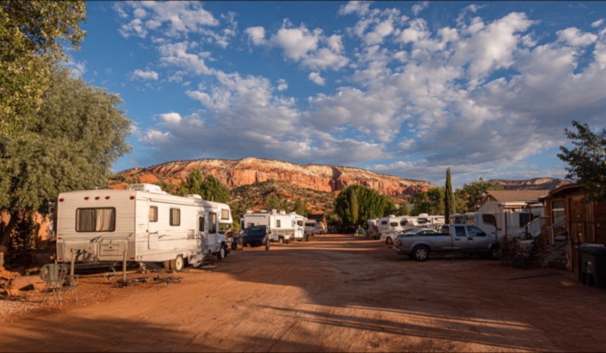 Recreational vehicles parked in a campground with red rock hills in the background